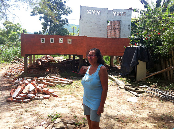 Image of a Maria outside her collapsed home