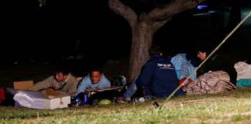 People sleeping outside under a tree